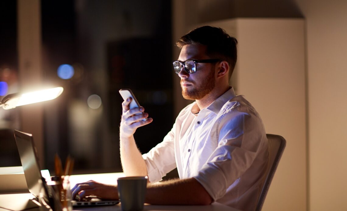 businessman texting on smartphone at night office