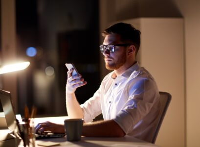 businessman texting on smartphone at night office