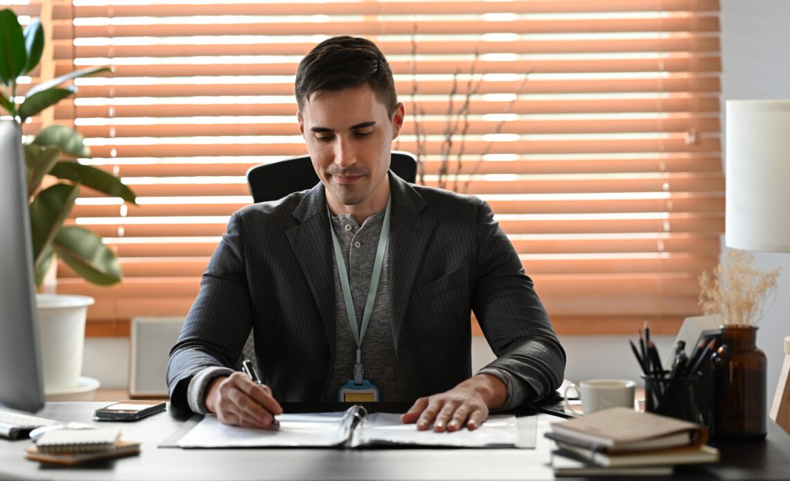 Handsome businessman in suit working with computer at modern office.