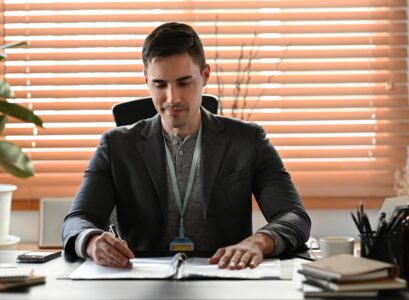 Handsome businessman in suit working with computer at modern office.