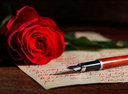 Red rose and an ink pen on a letter