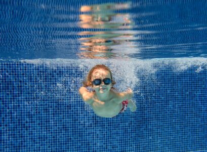Smiling boy swimming underwater in pool