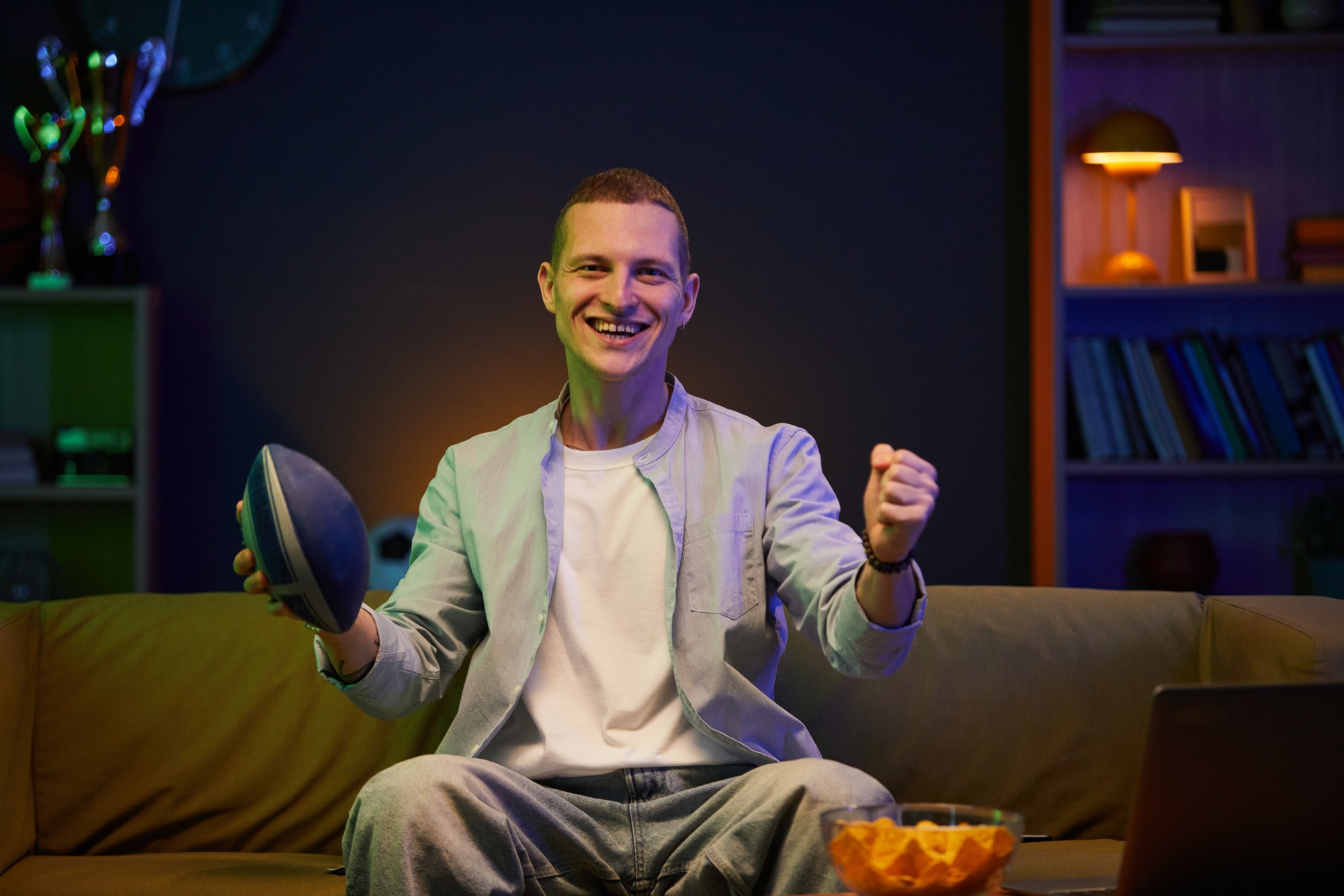 Smiling Man Holding Football While Watching Television